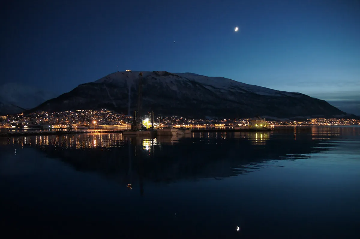 Lyngen Alps rising above fjord waters in Tromsø region, snow-covered mountain range