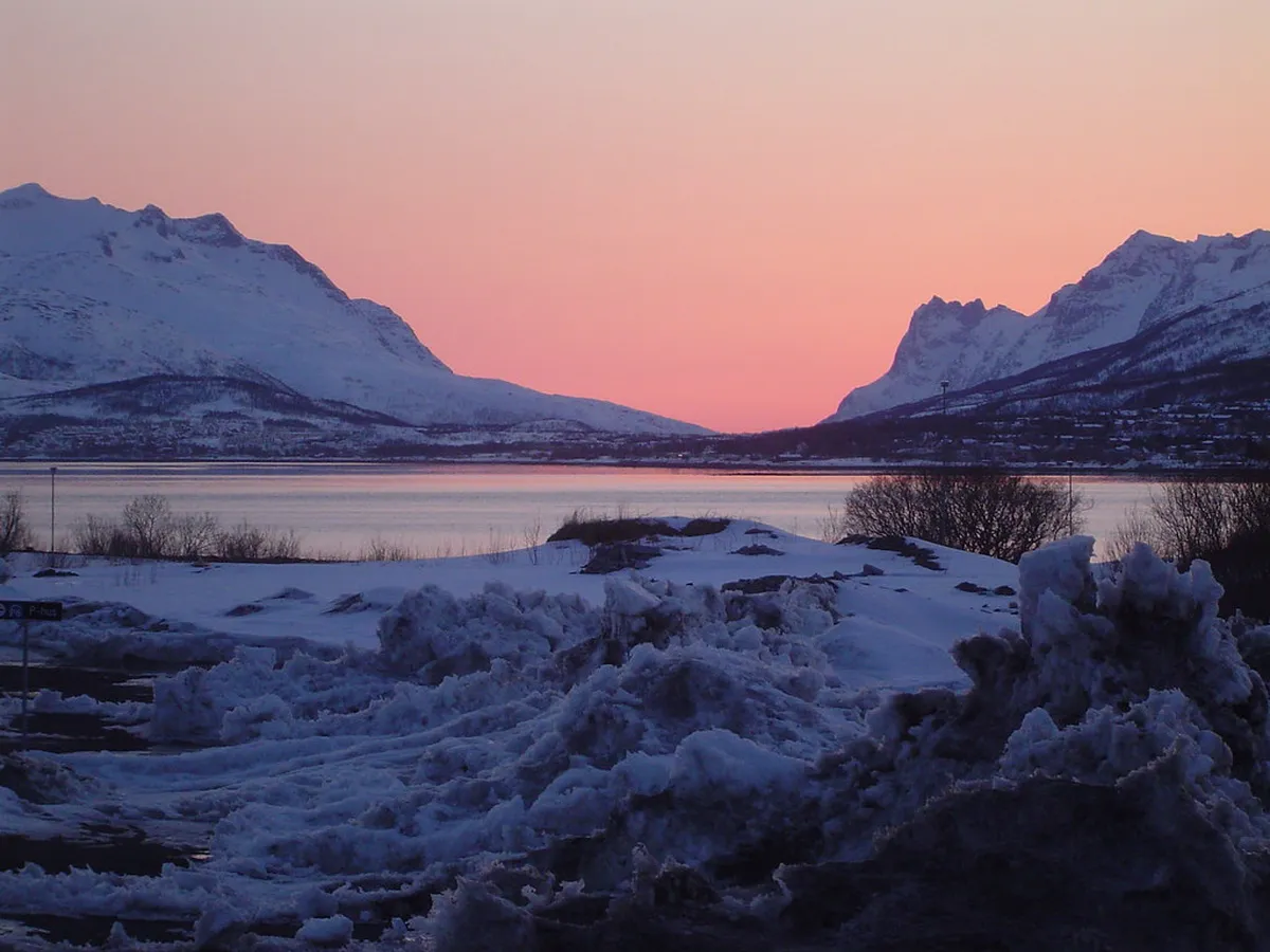 Panoramic fjord views from Storsteinen ledge in Tromsø, showing mountains, water, and Arctic landscape stretching to the horizon