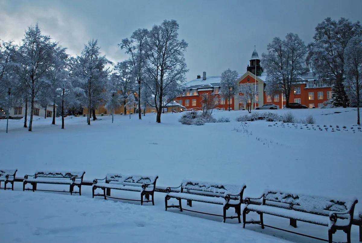 Snowy street in Tromsø during polar night with winter lighting, ice conditions, and pedestrians with reflectors during Arctic darkness