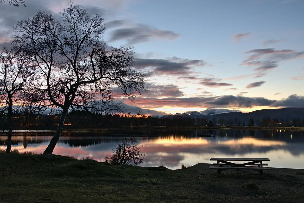 Prestvannet Lake in Tromsø with surrounding birch forests and mountain reflections in still water, Arctic Norway