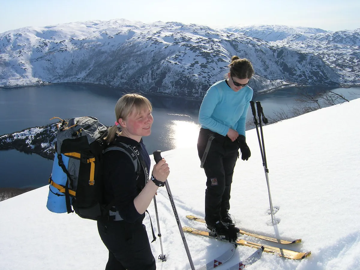 Skier descending pristine snow-covered slopes in the Lyngen Alps, Tromsø, Norway with fjord valley below