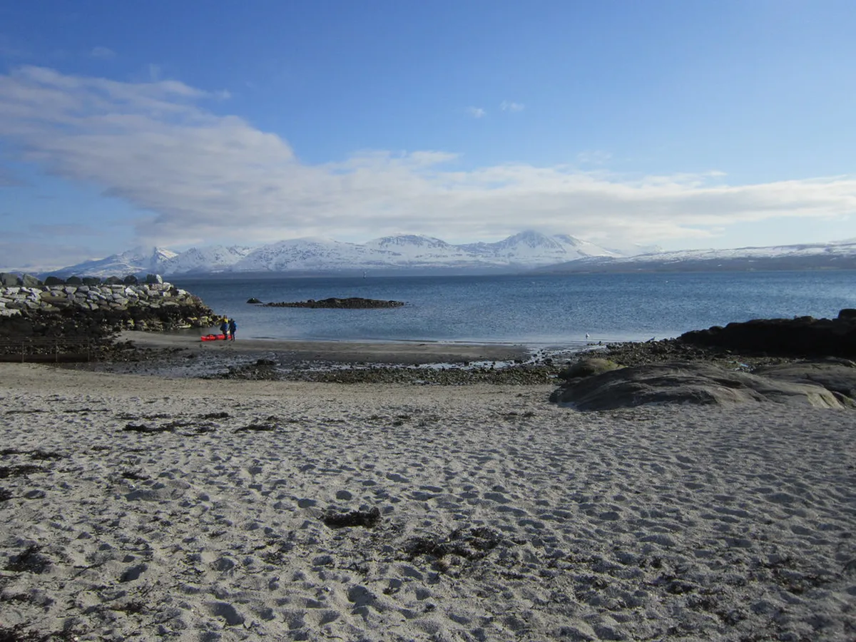 Telegrafbukta beach at dusk with calm fjord waters and Arctic snow-capped peaks in Tromsø, Norway