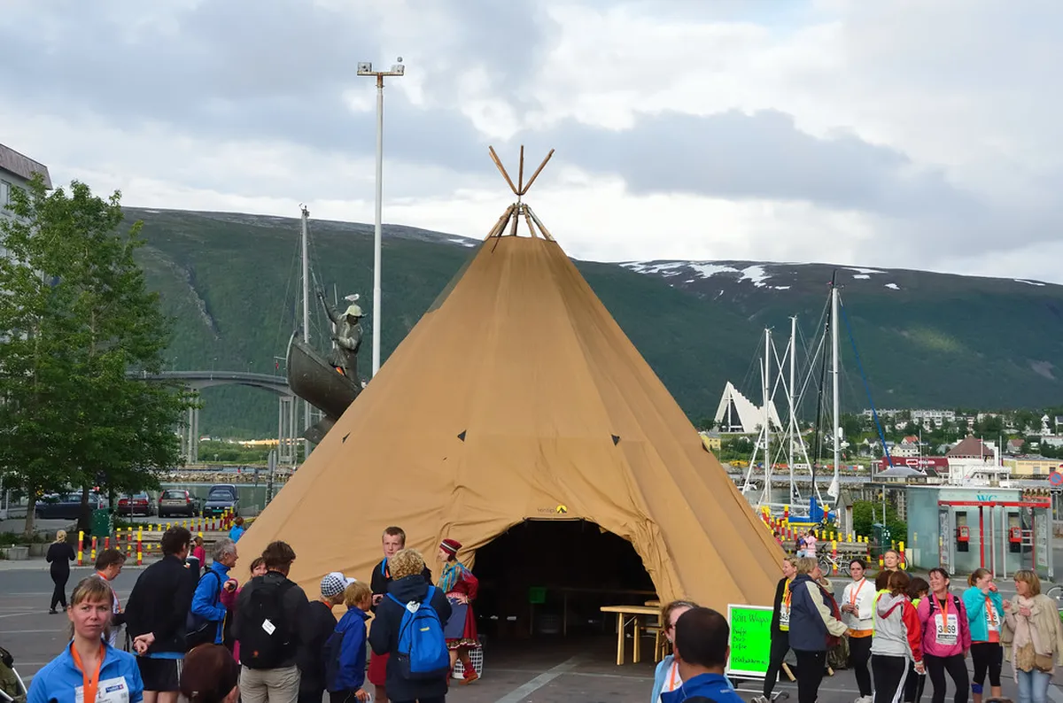 Traditional Sami lavvu tent in Tromsø with snow and smoke opening visible during Arctic winter