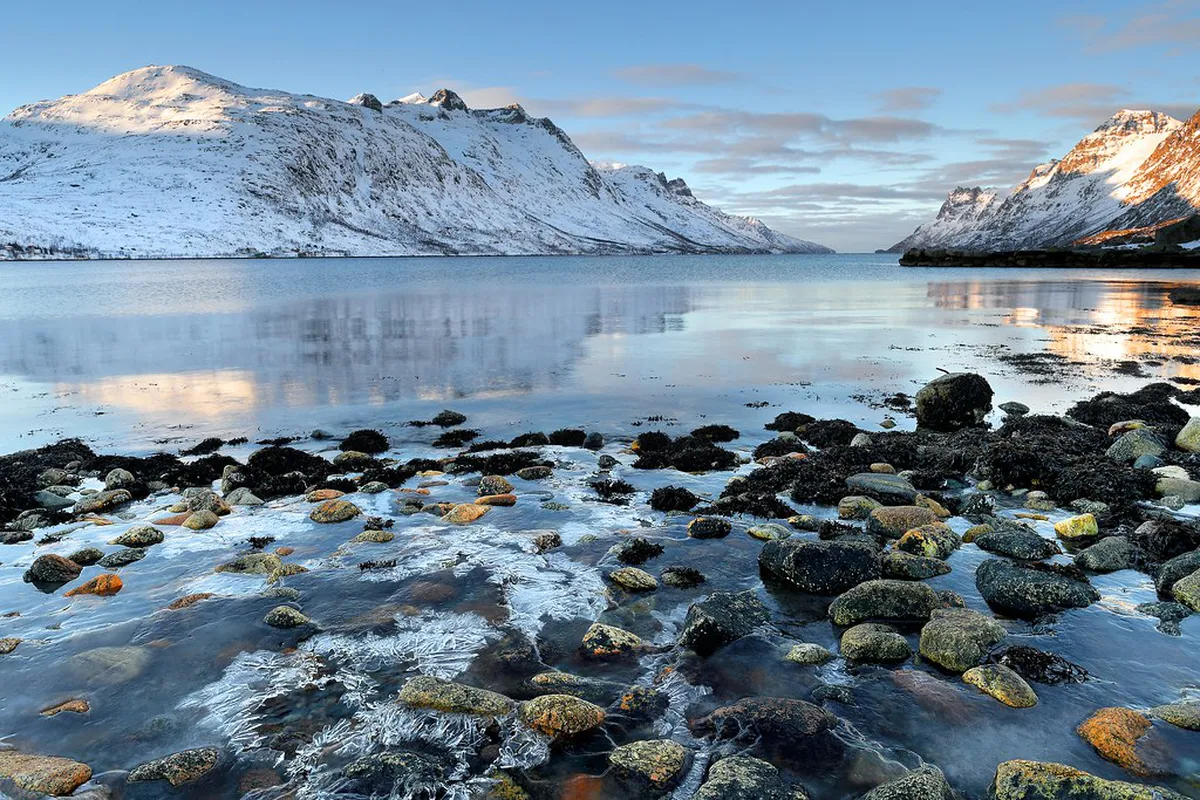 Turquoise Arctic waters and white shell-sand beach at Sommaroy, Tromsø, with colorful fishing cottages