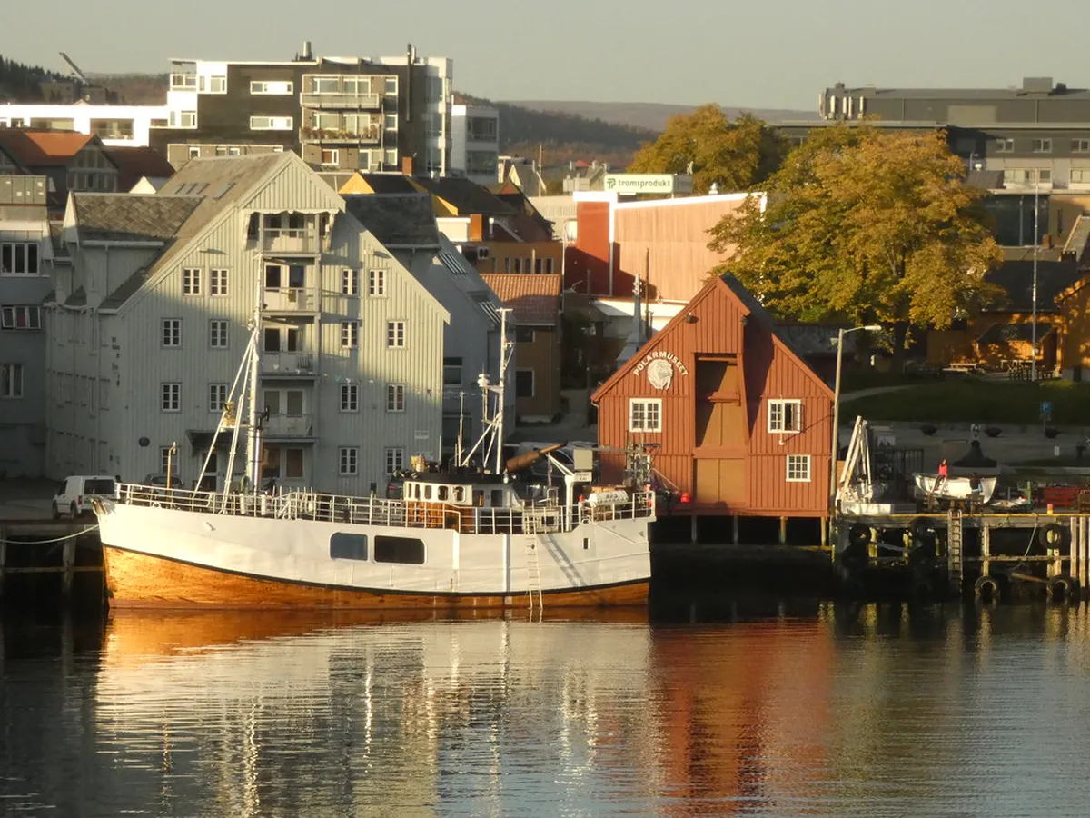 Vulkana spa boat moored in Tromsø harbour with Arctic mountains in the background, sauna and hot tub experience