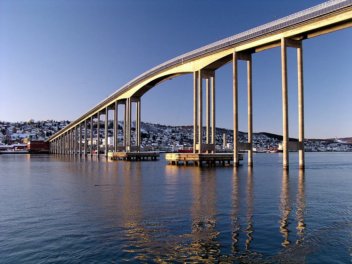 The iconic Tromsø Bridge spanning the Arctic waters, offering panoramic views of the city, mountains, and harbor that make it one of the most photographed and costless attractions in Tromsø