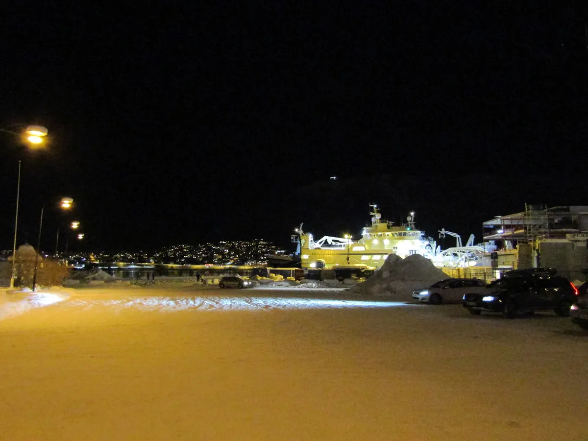 Tromsø waterfront harbour at dusk with fishing boats and Arctic Cathedral reflected in still water