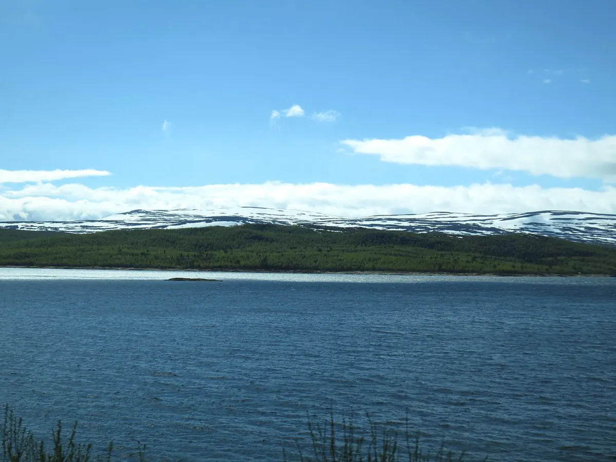 Frozen Swedish Lapland lake surrounded by snow-covered landscape, classic aurora viewing location in Abisko National Park