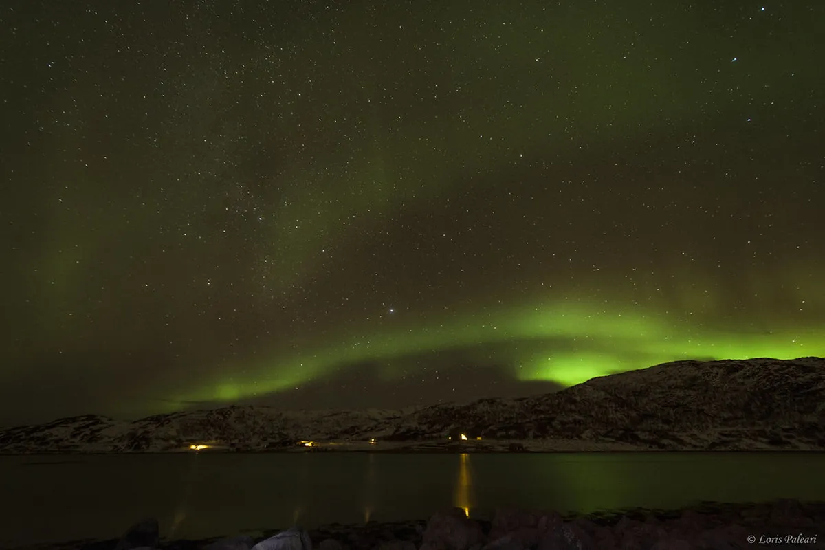 Northern lights aurora borealis dancing over Kvaløya island, Arctic sky with green lights